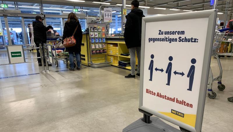 Ein Hinweisschild bittet die Kunden im Kassenbereich Abstand zum nächsten Kunden zu halten. Foto: Alexander Blum/dpa Ein Hinweisschild bittet die Kunden im Kassenbereich Abstand zum nächsten Kunden zu halten. Foto: Alexander Blum/dpa