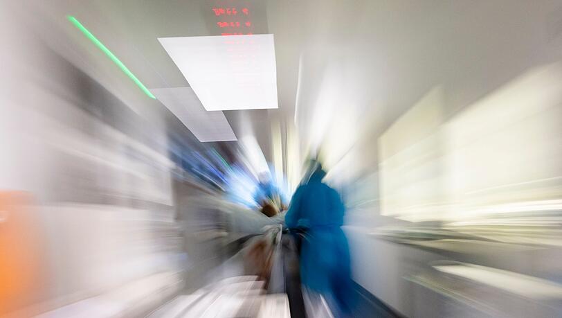 Pflegekräfte transportieren einen Patienten auf einem Gang einer Intensivstation (Zoomeffekt durch lange Belichtungszeit).