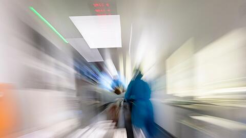 Pflegekräfte transportieren einen Patienten auf einem Gang einer Intensivstation (Zoomeffekt durch lange Belichtungszeit).
