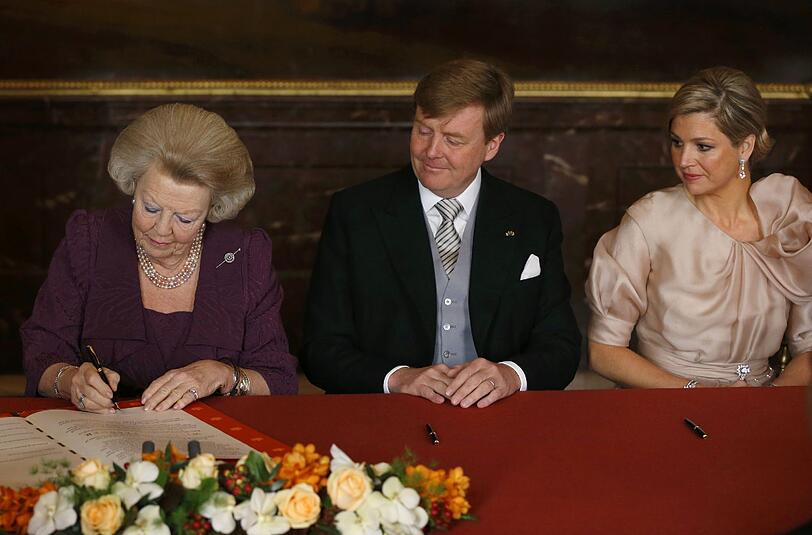 Königin Beatrix unterzeichnet ihre Abdankungsurkunde. An ihrer Seite der neue König Willem-Alexander und Maxima.