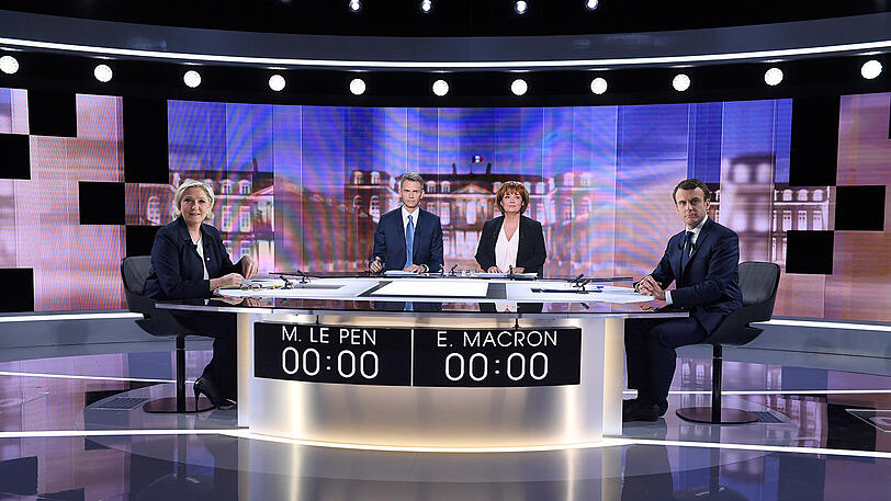 Zoffen sich live im Fernsehen: Rechtspopulistin Marine Le Pen (l.) und ihr sozialliberaler Gegner Emmanuel Macron (r.) sitzen zu Beginn der TV-Debatte in Plaine-Saint-Denis, nördlich von Paris. Die Journalisten Christophe Jakubyszyn (2. v. l.) und Nathalie Saint-Cricq moderieren.
