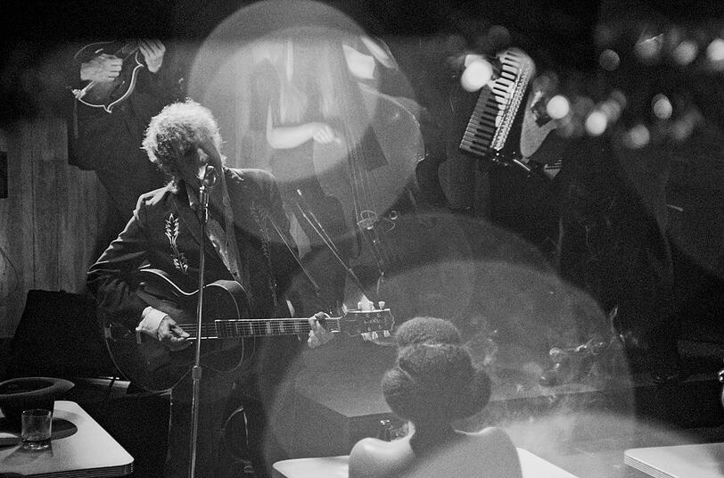 Songwriter-Legende Bob Dylan spielt einige ihrer größten Hits mit einer akustischen Live-Band im Retro-Look. Die Location: eine Bar voller rauchender und trinkender Menschen im Stil der 30er oder 40er. Songwriter-Legende Bob Dylan spielt einige ihrer größten Hits mit einer akustischen Live-Band im Retro-Look. Die Location: eine Bar voller rauchender und trinkender Menschen im Stil der 30er oder 40er.