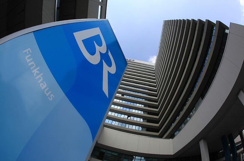 Blaues Sender-Logo vor weißblauem Himmel: das Hochhaus des Bayerischen Rundfunks an der Arnulfstraße.	F