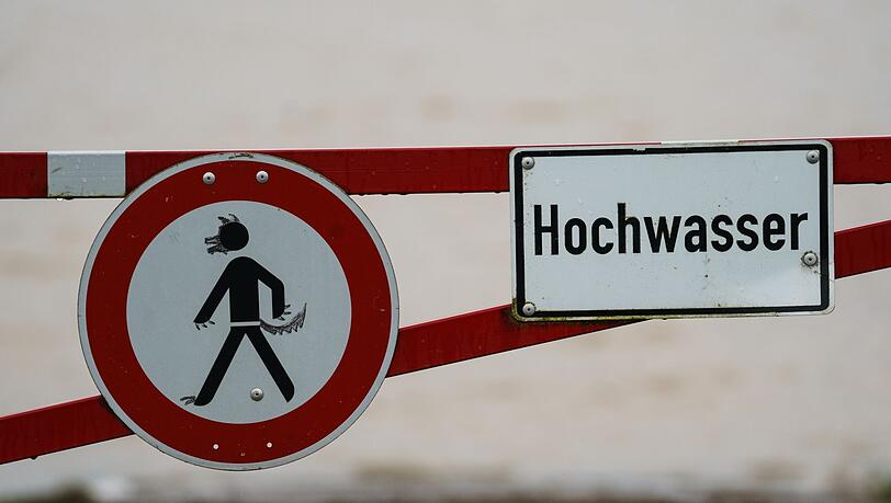 Ein Hochwasser-Schild steht an einem überfluteten Feld.