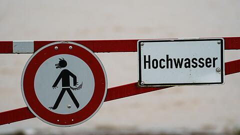Ein Hochwasser-Schild steht an einem überfluteten Feld.