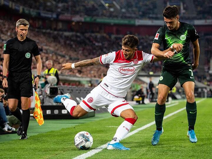 Düsseldorfs Matthias Zimmermann (l) spielt beim Dull mit dem Wolfsburger Josip Brekalo einen Ball im Aus.