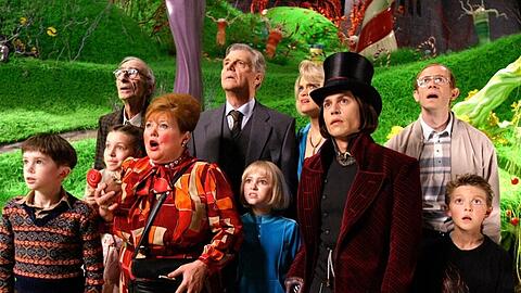 Willy Wonka führt Kinder und deren Begleitpersonen in seinem Schoko-Imperium herum