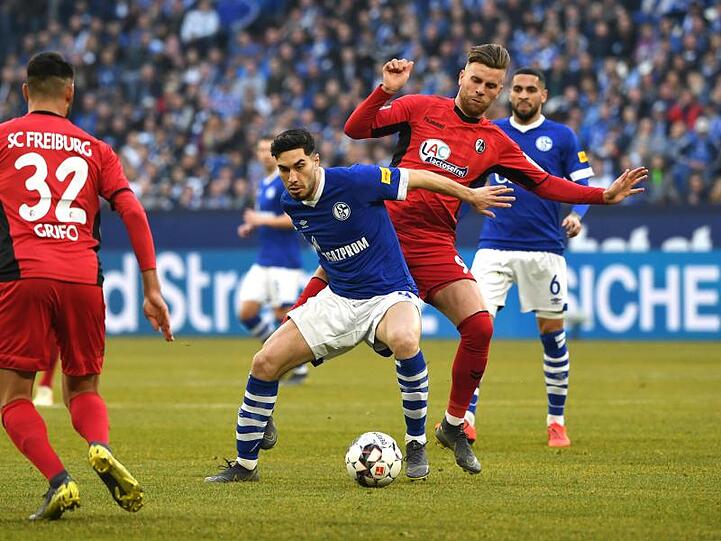 Schalkes Suat Serdar beim Zweikampf mit dem Freiburger Lucas Höler (r).
