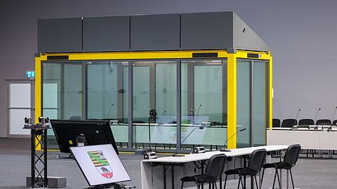 Ein Blick in den Gerichtssaal auf den Platz für die Zeugen und die Glaskabine, in der der Angeklagte während der Verhandlungen sitzt. (Archivbild)