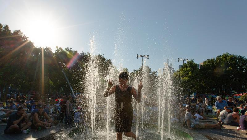 Eine Frau erfrischt sich in kompletter Kleidung in einem Brunnen im Melbourne Park ab. Eine Frau erfrischt sich in kompletter Kleidung in einem Brunnen im Melbourne Park ab.