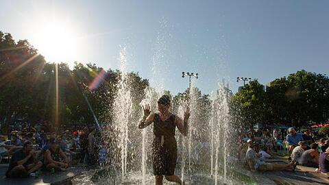 Eine Frau erfrischt sich in kompletter Kleidung in einem Brunnen im Melbourne Park ab.