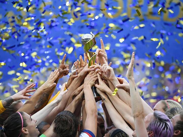 Die US-Spielerinnen feiern ihren Sieg und halten gemeinsam den WM-Pokal nach oben.