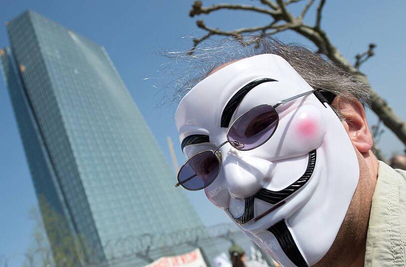 Ein Demonstrant mit einer Guy Fawkes Maske steht auf einer Anti-EZB-Demonstration in Frankfurt am Main vor dem Neubau der Europäischen Zentralbank.