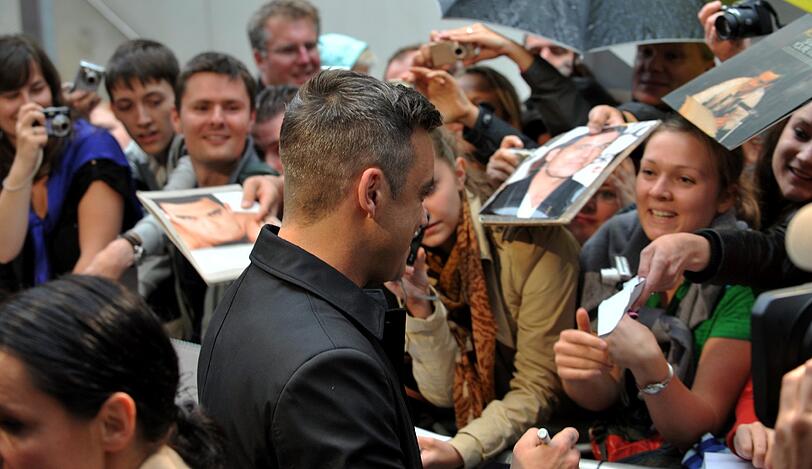 Weltstar im Fan-Gewusel: Robbie Williams verteilte Autogramme vor dem Mathäser-Kino.