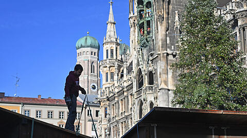 Arbeiter bauen die Standl für den Christkindlmarkt am Marienplatz auf.