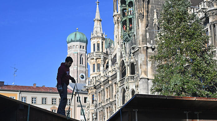 Arbeiter bauen die Standl für den Christkindlmarkt am Marienplatz auf.