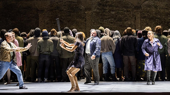 Corinne Winters (Katja) schlägt mit dem Stock der Kabanicha um sich. Um sie herum: Benjamin Hulett (Kudrjáš), Jaroslav Březina (Tichon) und Kabanicha (Evelyn Herlitzius) und die aus Puppen und Kleindarstellern zusammengesetzte Masse am Ende des zweiten Akts von Janáčeks Oper.