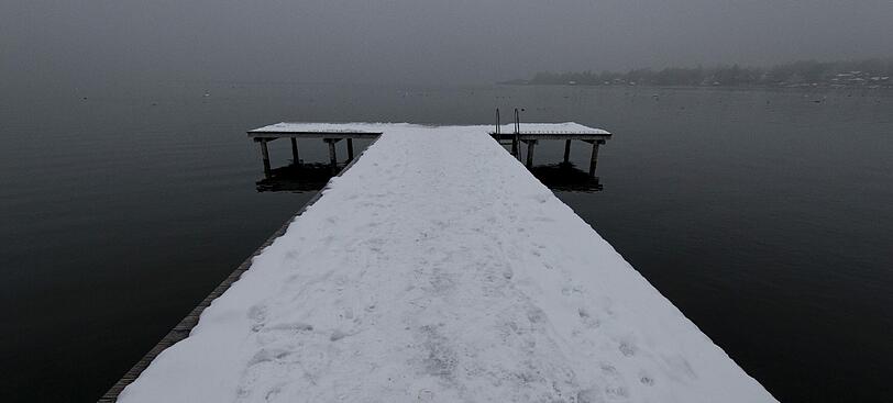 Der Ammersee bei Herrsching. Ein Steg ist zugeschneit.