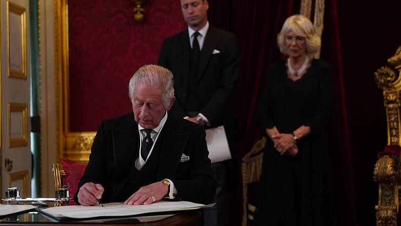 König Charles III. unterschreibt im Beisein seines Sohnes, Prinz William, und seiner Gemahlin, Königin Camilla, einen Eid.