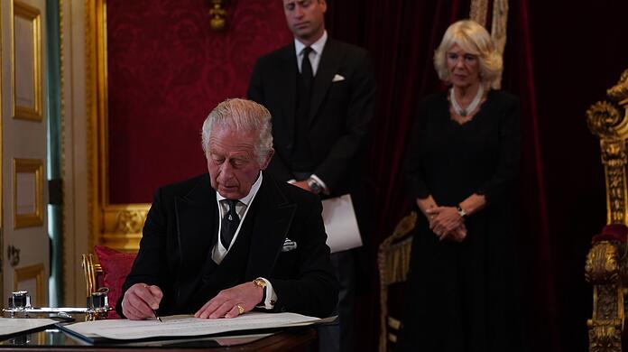 König Charles III. unterschreibt im Beisein seines Sohnes, Prinz William, und seiner Gemahlin, Königin Camilla, einen Eid.