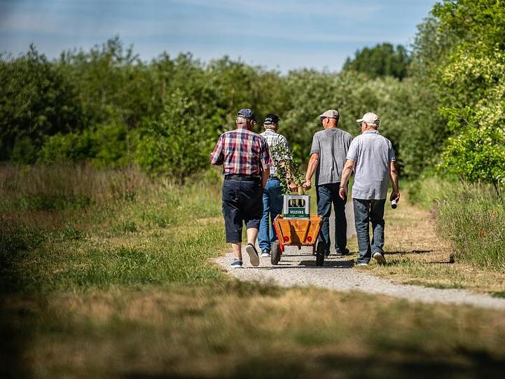 Traditionalisten: Vier Männer gehen am Vatertag mit einem Bollerwagen, auf dem zwei Kisten Bier stehen, an der Ems in Warendorf entlang.
