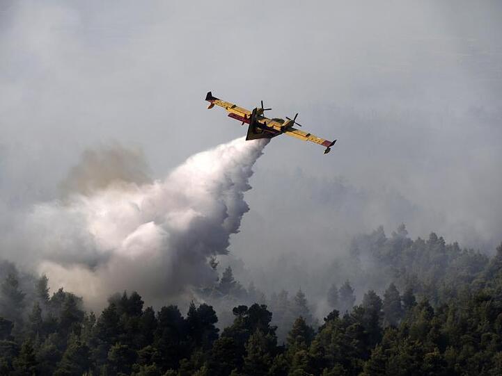Ein Löschflugzeug lässt Wasser über einem Wald auf der griechischen Insel Euböa ab.