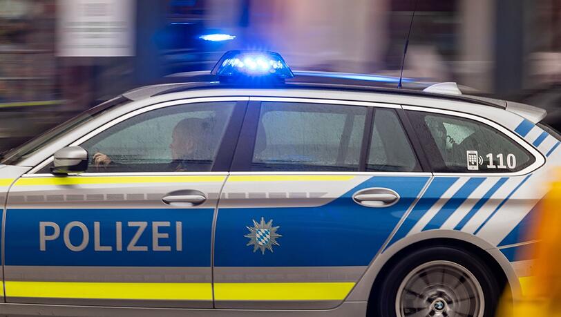 Ein Fahrzeug der bayerischen Polizei fährt mit Blaulicht durch die Innenstadt. (Symbolbild)
