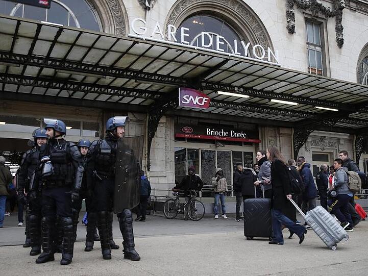 Reisende am Gare de Lyon, der während einer Demonstration der streikenden Eisenbahner von Polizisten bewacht wird.