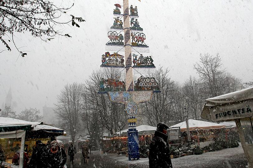 Ein Maibaum im Schneetreiben: Auch der Viktualienmarkt zeigt sich derzeit noch recht winterlich.