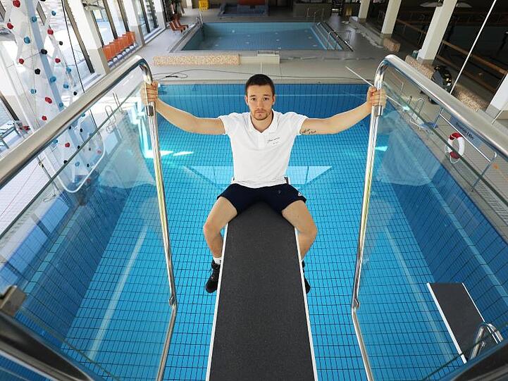 Der Schwimmmeister Thomas Dyck sitzt im leeren Zollstockbad in Köln auf einem Sprungbrett.