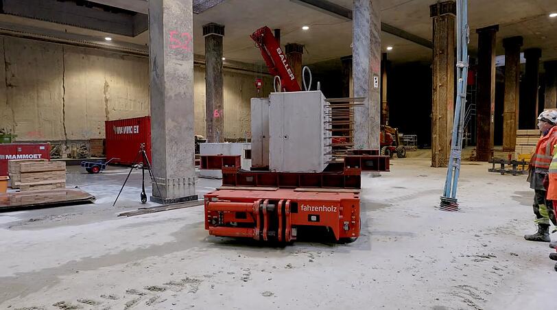 Massive Stahlbeton-Fertigteile werden mit sogenannten Tausendfüßlern an ihre richtige Position verschoben.