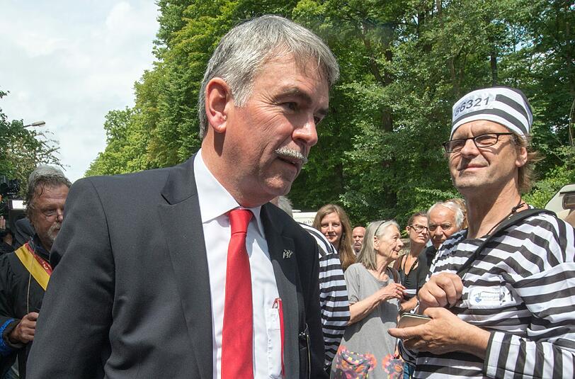 Gustl Mollath geht am 07.07.2014 neben einem als Sträfling verkleideten Unterstützer vor dem Landgericht in Regensburg. Knapp ein Jahr nach seiner Entlassung aus der Psychiatrie steht Mollath erneut vor Gericht.
