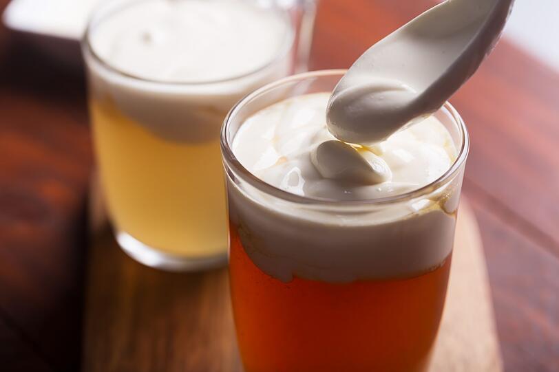 Danach einen Teel&ouml;ffel gezuckerte Kondensmilch, einen Teel&ouml;ffel Frischk&auml;se, 20 Milliliter Milch und eine Prise Salz glatt r&uuml;hren. Dann die steif geschlagene Sahne vorsichtig unterheben. Die fertige Creme als Topping auf den lauwarmen Tee geben. Am besten zuerst das Frischk&auml;se-Topping mit dem L&ouml;ffel genie&szlig;en und dann den Tee trinken. Denn wenn sich beides vermischt, geht der typische K&auml;segeschmack schnell verloren.