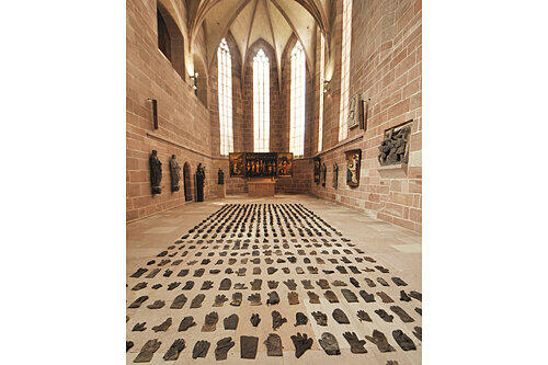 Gotische Skulpturen und Relikte von Zwangsarbeit: Raffael Rheinsbergs Installation mit Handschuhen und Schuhen in der Nürnberger Kartäuserkirche, als Teil der deutsch-deutschen Kunst-Retrospektive.