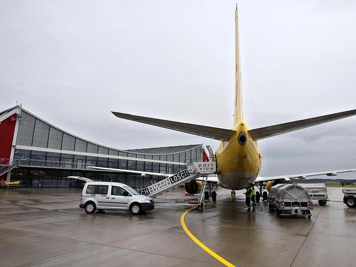 Flughafenmitarbeiter laden auf dem Allgäu Airport Gepäck aus einer soeben gelandeten Maschine. Foto: Karl-Josef Hildenbrand/Archiv