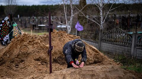 Die 63-jährige Vera Ptitsyna legt Blumen auf das frische Grab ihres Mannes Jurij Ptitsyn. Der 74-Jährige starb während der einmonatigen russischen Besetzung von Butscha infolge mangelnder medizinischer Versorgung.