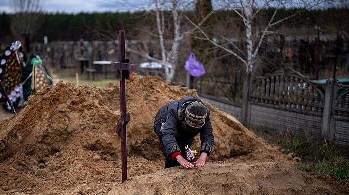 Die 63-jährige Vera Ptitsyna legt Blumen auf das frische Grab ihres Mannes Jurij Ptitsyn. Der 74-Jährige starb während der einmonatigen russischen Besetzung von Butscha infolge mangelnder medizinischer Versorgung.