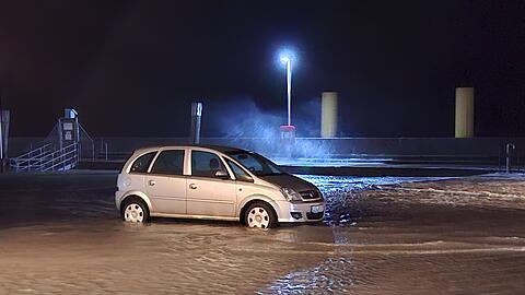 In Wilhelmshaven steht ein Auto auf einem überfluteten Parkplatz.