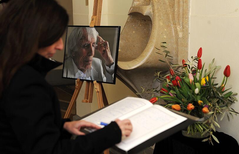Eine Frau trägt sich am Freitag (30.12.2011) in München (Oberbayern) am Nordfriedhof vor Beginn der Trauerfeier für Johannes Heesters in das Kondolenzbuch ein.