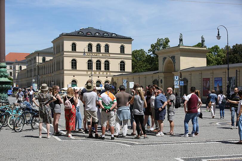 In praller Sonne: Touristen lauschen am Odeonsplatz.