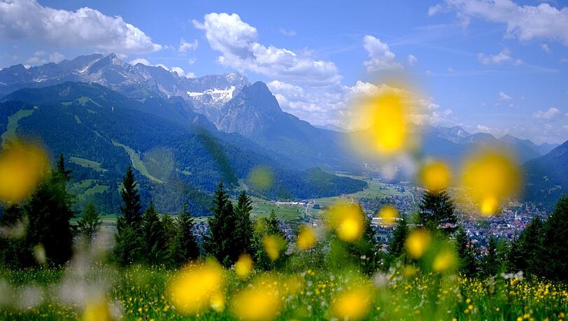 Sommer in den Bergen: Der Wank in Bayern ist ein beliebtes Reiseziel, auch für die Bürger im Freistaat selbst. Im Hintergrund sind die Gipfel des Wettersteins mit der Zugspitze zu sehen. Aber: der Urlaub in Bayern wird immer teurer.