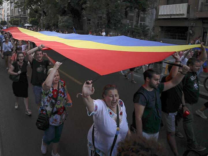 Menschen halten eine rumänische Flagge während einer Demonstration zum Gedenken an ein getötetes 15-jähriges Mädchen in Bukarest.