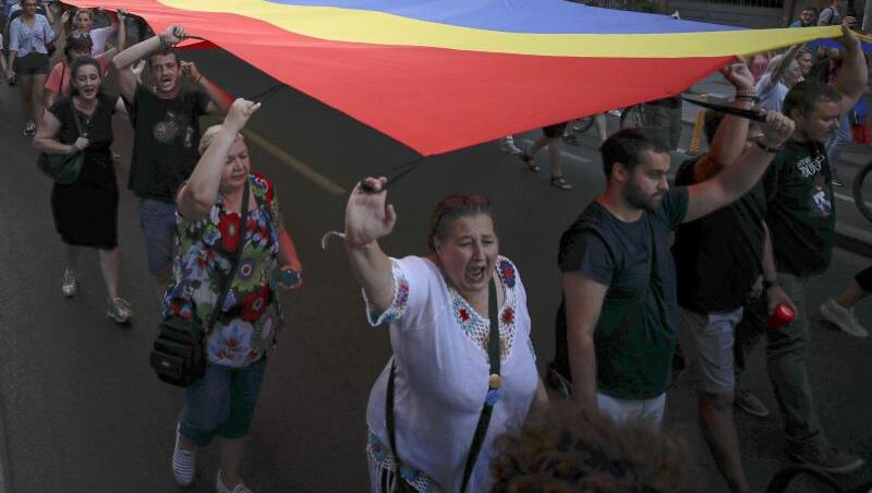 Menschen halten eine rumänische Flagge während einer Demonstration zum Gedenken an ein getötetes 15-jähriges Mädchen in Bukarest. Menschen halten eine rumänische Flagge während einer Demonstration zum Gedenken an ein getötetes 15-jähriges Mädchen in Bukarest.