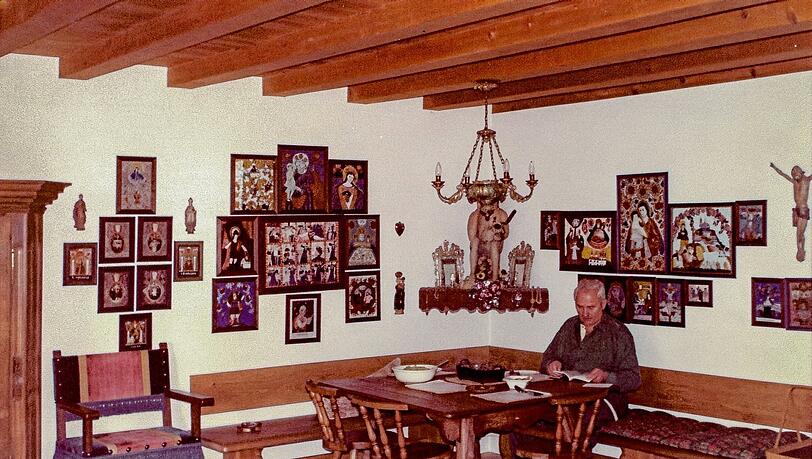 Der Roider Jackl, umgeben von Hinterglasbildern und religi&ouml;ser Volkskunst, in seinem Freisinger Wohnzimmer.
