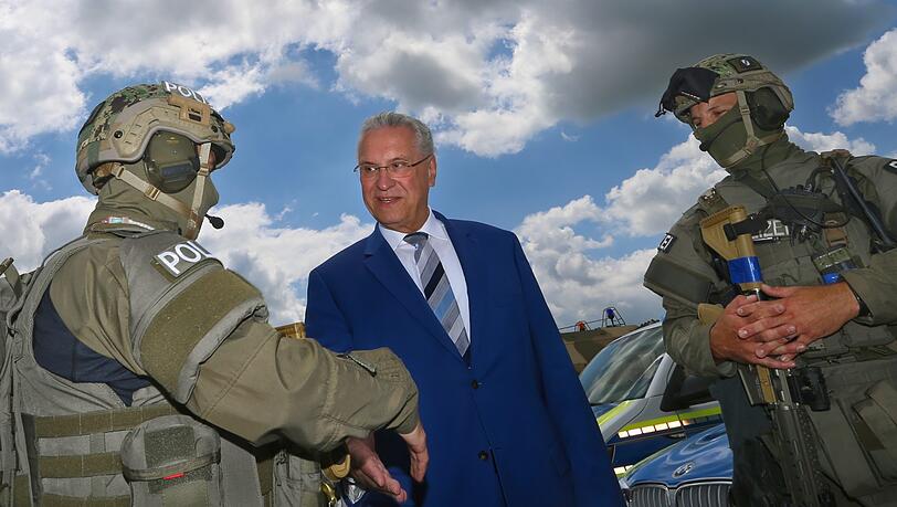 Innenminister Joachim Herrmann (CSU) spricht bei einer Übung auf dem Fliegerhorst Penzing mit zwei Polizisten des SEK.