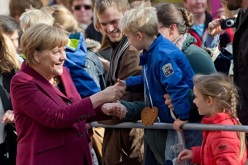 Auf Augenhöhe mit den Kleinsten: Kanzlerin Angela Merkel schüttelt bei ihrer Ankunft in Nürnberg einem Bub die Hand.
