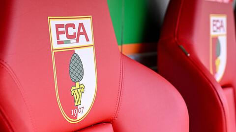 Das Logo des FC Augsburg ist auf Sitzen in der WWK-Arena zu sehen.