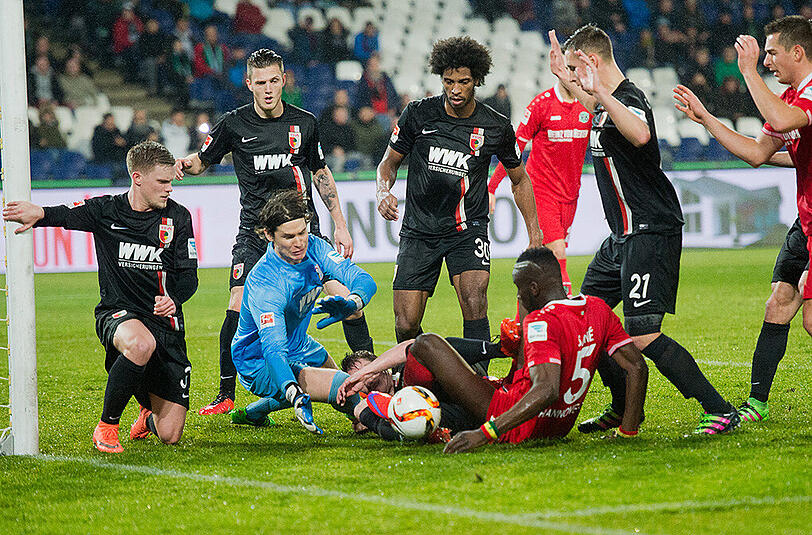 Wildes Getümmel im Augsburger Strafraum: Torwart Marwin Hitz, Augsburgs Paul Verhaegh und Hannovers Salif Sane kämpfen um den Ball, die Augsburger Philipp Max (von links nach rechts), Jeffrey Gouweleeuw, Caiuby und Dominik Kohr schauen zu.
