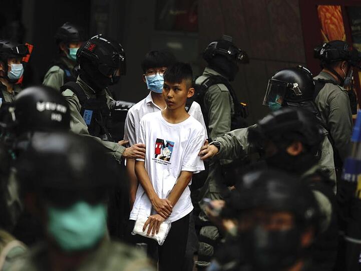 Bereitschaftspolizisten halten im Zentrum von Hongkong zwei junge Demonstranten fest.