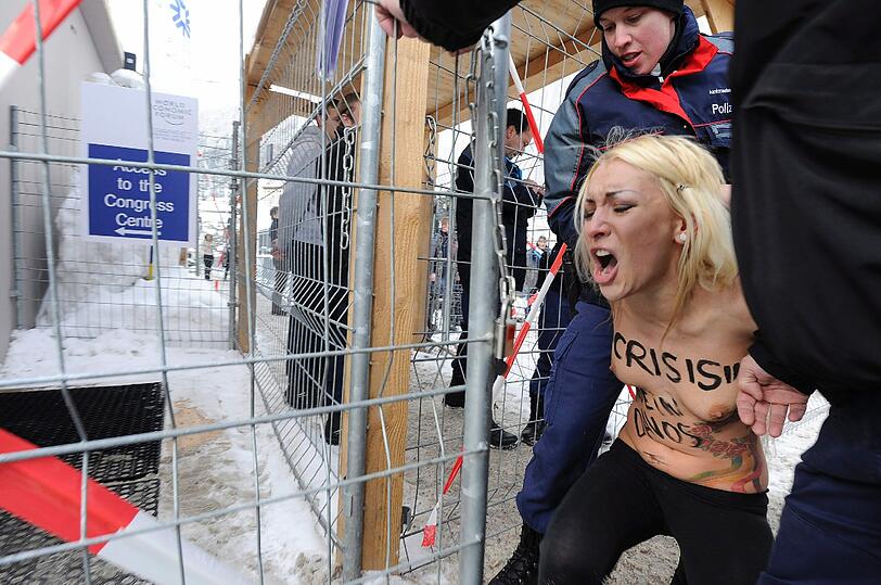 Nacktprotest in Davos: Ukrainerinnen demonstrieren barbusig am Zaun vor dem Weltwirtschaftsforum. Die Polizei greift ein - die Bilder.